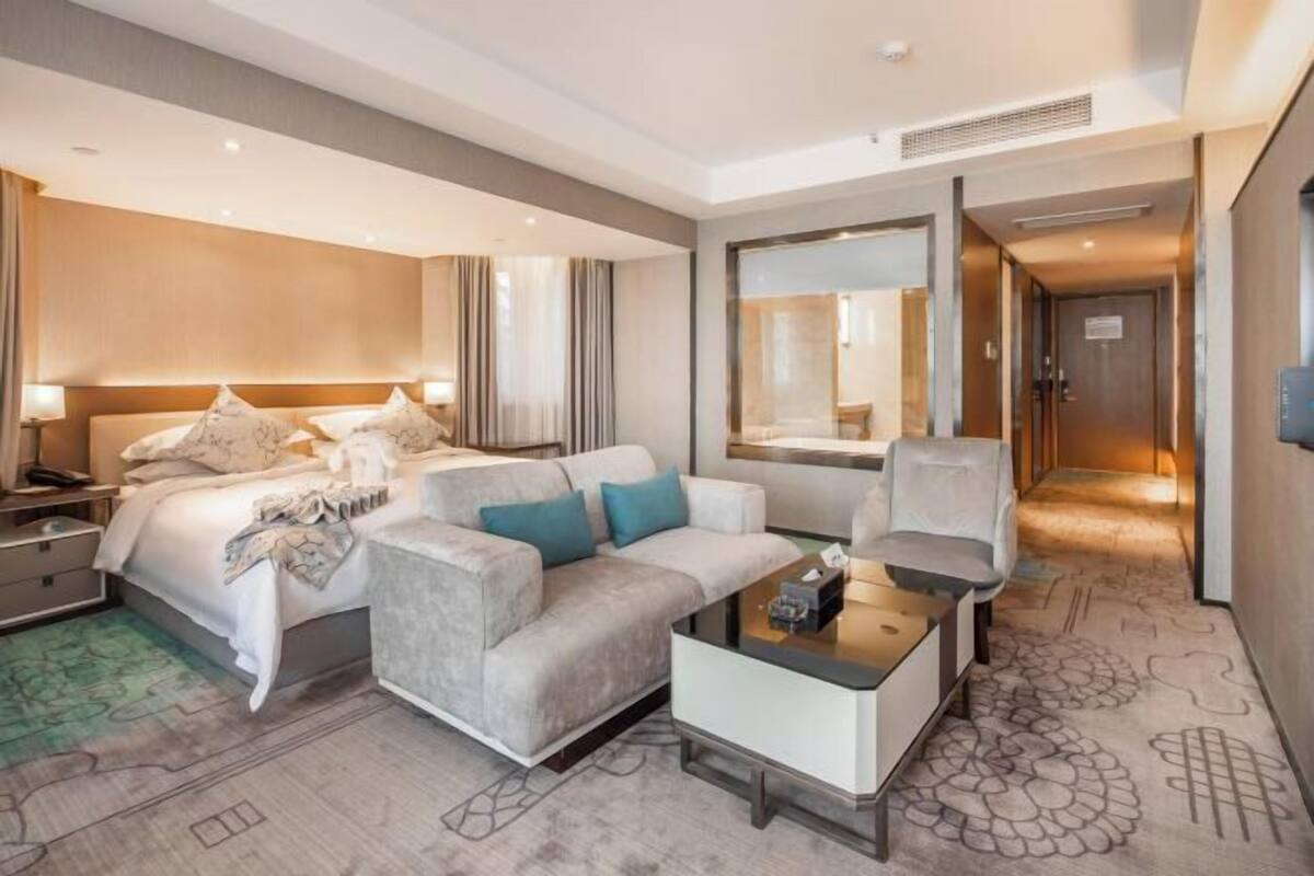 Ein modernes Hotelzimmer mit Bett, Sofa, Couchtisch und Schreibtisch.