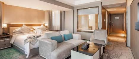 A modern hotel room with a bed, a sofa, a coffee table, and a desk.