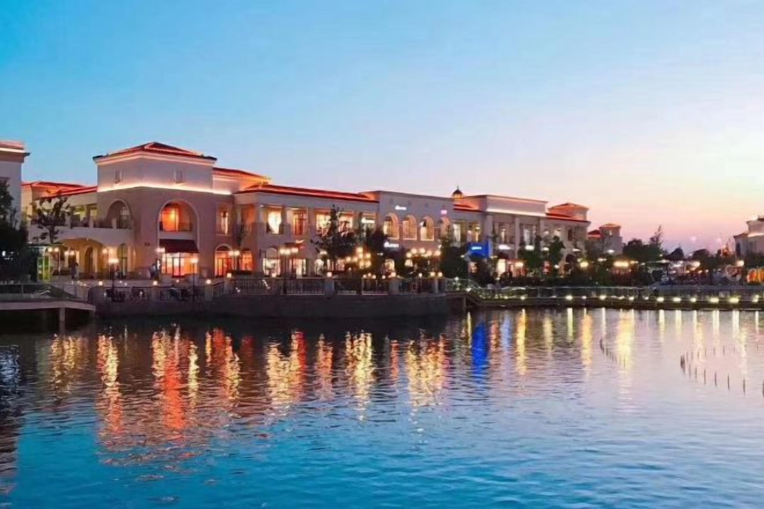 A waterfront hotel with a reflective pool, multiple stories, and a prominent building facade.