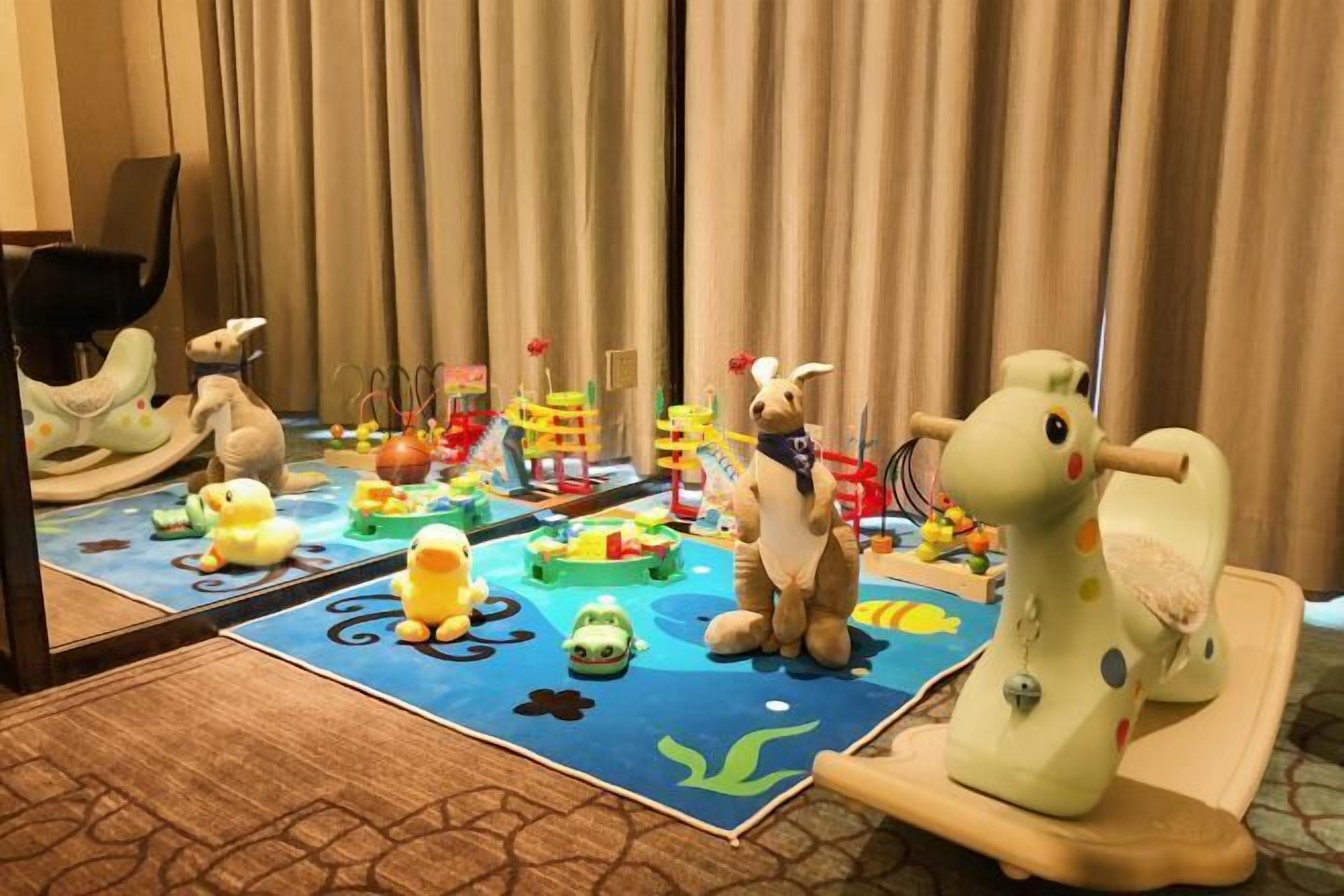 Zona de juegos infantiles con juguetes y un espejo que refleja la habitación.
