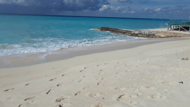 Ein Strand mit klarem türkisblauem Wasser, einem Sandstrand und einem Rettungsturm.