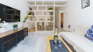 Ein modernes Wohnzimmer mit Fernseher, einer Couch, einem Essbereich und einem Bücherregal.