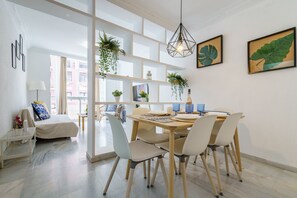 Et moderne spiseområde med et træbord, hvide stole og hængende planter.