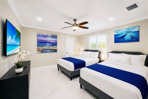 A hotel room with two beds, a ceiling fan, artwork on the walls, a TV, and a potted plant. - Deluxe 5BR/3BA Villa in Hollywood Lakes near Beach (Hollywood)