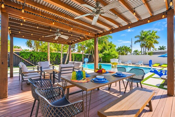 An outdoor patio with a pool, wooden deck, and seating area.