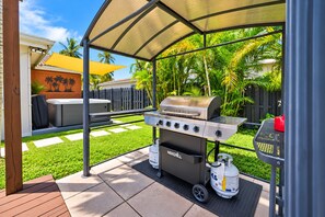 An outdoor grill setup with a canopy, a portable gas tank, and a seating area with a table and chairs. - Deluxe 5BR/3BA Villa in Hollywood Lakes near Beach (Hollywood)