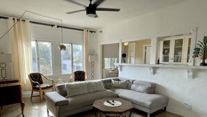 Un soggiorno con un divano componibile, due poltrone, un tavolino e una ventola a soffitto.