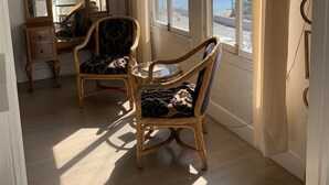 Una stanza con un'ampia finestra, un tavolo rotondo e due sedie in vimini.