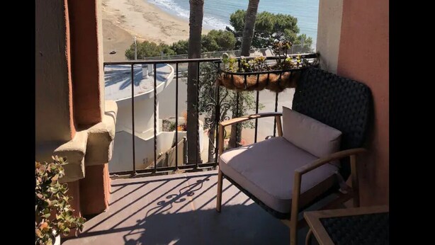 Un balcone con vista sulla spiaggia e palme.