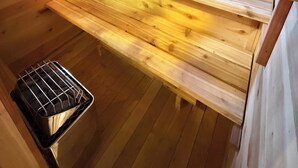 Un interno in legno con una finestra, un lavandino e una rastrelliera metallica.