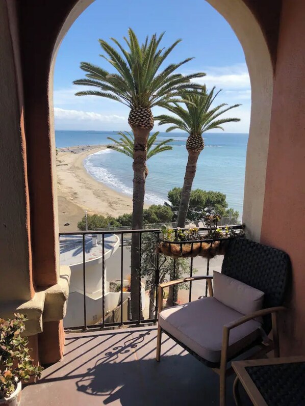 Un balcón con vista a una playa y palmeras.