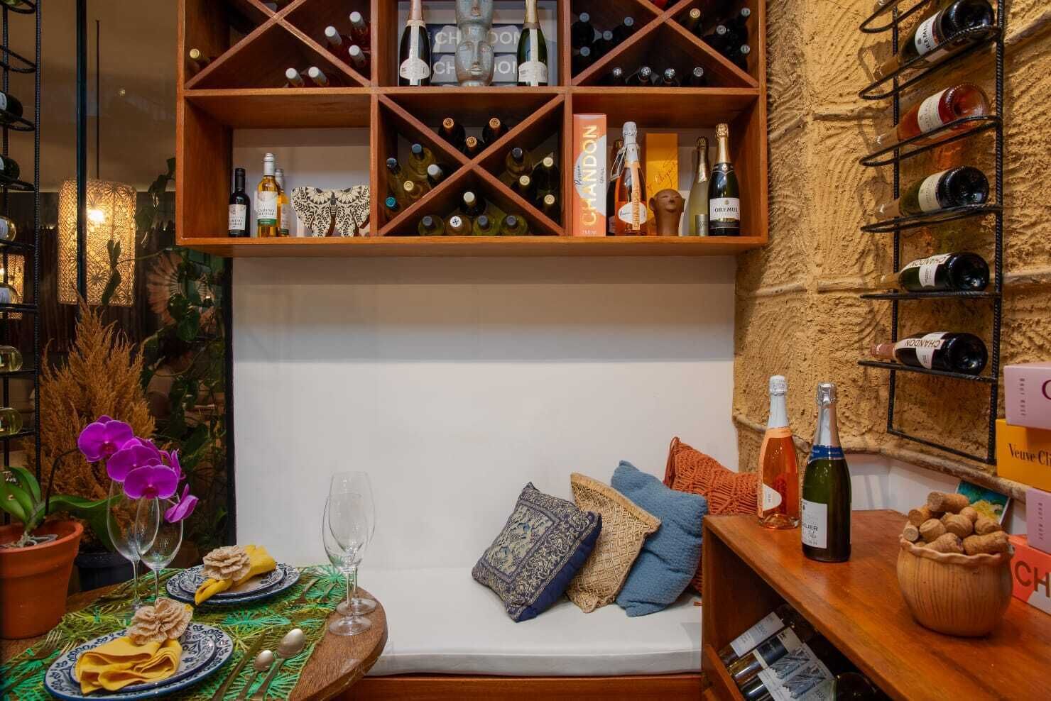 A cozy seating area with a wine rack, a bottle of champagne, and a bowl of nuts.