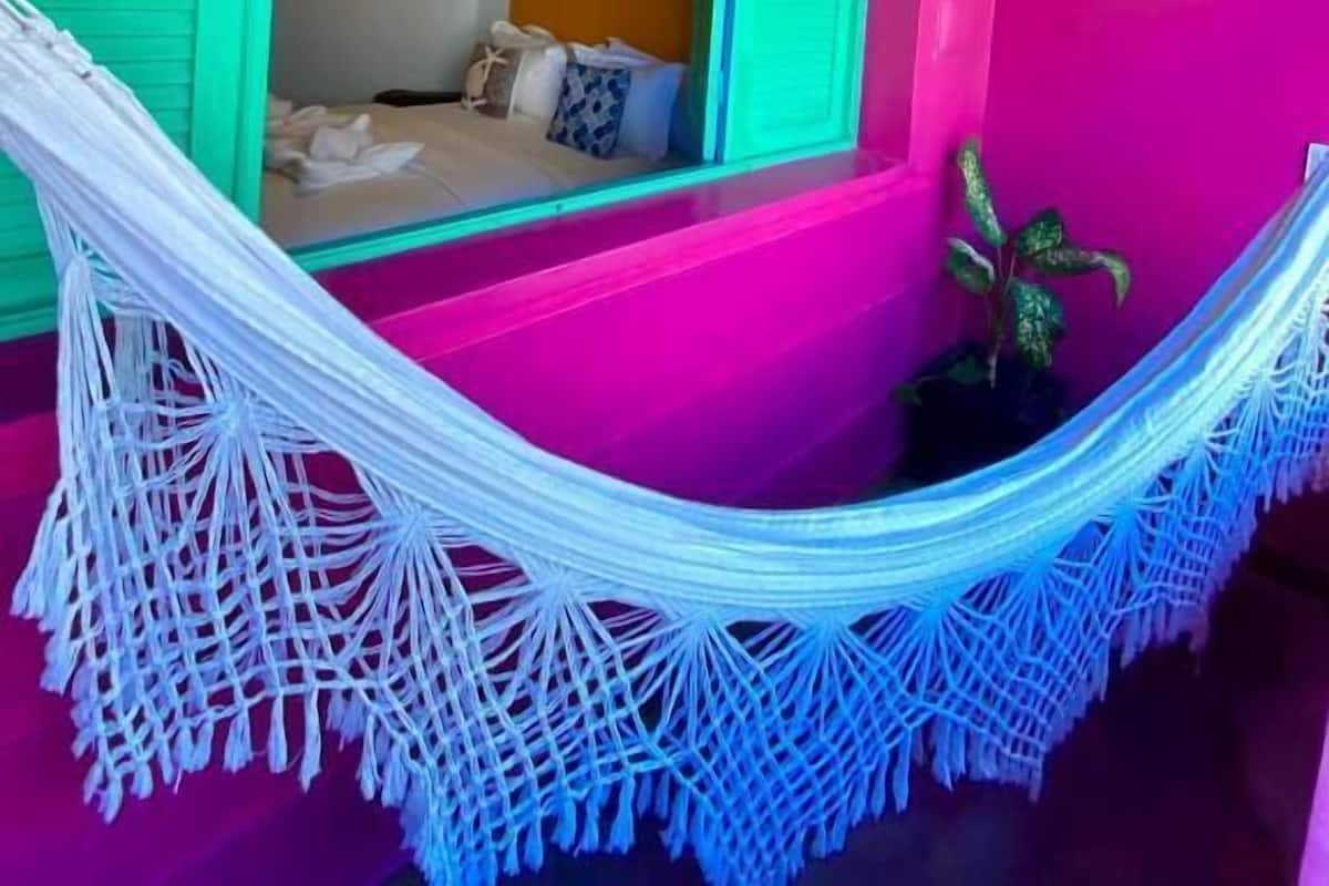 Ein Zimmer mit Hängematte, einem Bett mit Kissen und einem Deckenventilator.