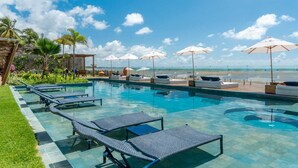A pool area with lounge chairs and umbrellas, a view of the beach, and a clear sky. - Villa Pantai Boutique Hotel Maragogi (Maragogi)