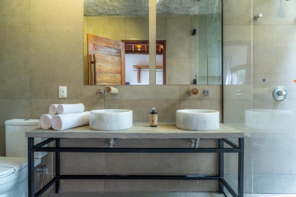 A modern bathroom with two sinks, a large mirror, and a shower area.