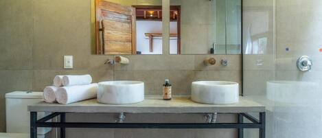 A modern bathroom with two sinks, a large mirror, and a shower area.