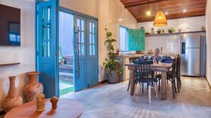 A spacious kitchen with a dining area, featuring a wooden ceiling, a blue door, and a modern stainless steel refrigerator. - Villa Pantai Boutique Hotel Maragogi (Maragogi)