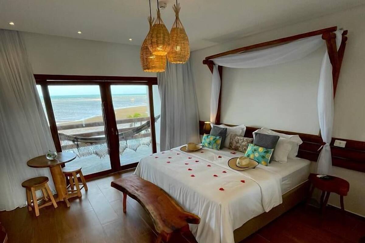 Ein Schlafzimmer mit einem großen Bett, einer Bank, einem kleinen Tisch und einer Topfpflanze.