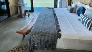 A modern bedroom with a large bed, a view of the ocean, and a unique chandelier. - Villa Pantai Boutique Hotel Maragogi (Maragogi)