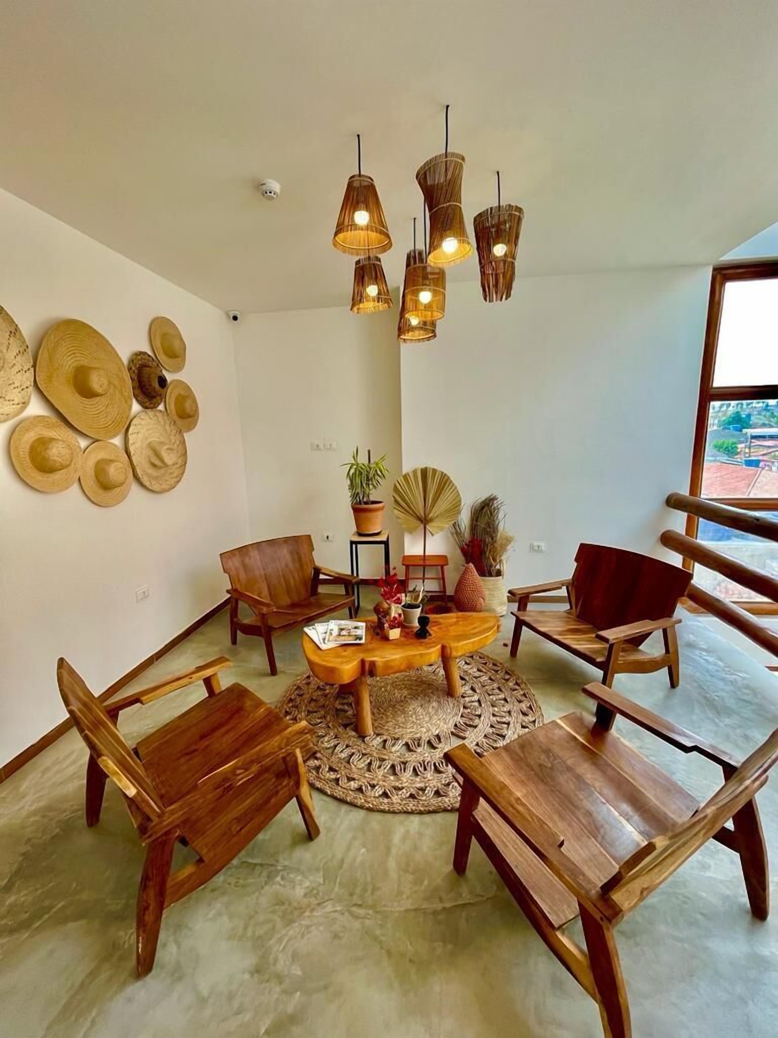 Un salon moderne avec une table basse ronde en bois, plusieurs chaises en bois et une grande fenêtre offrant une vue sur l’extérieur.