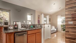 Una cocina moderna con lavavajillas, un lavabo y una encimera con varios objetos.