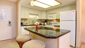 A modern kitchen with a central island, built-in appliances, and pendant lighting. - Maui Banyan ground floor 2 full baths,steps to Kamaole 2,great walking location. (Kihei)