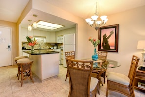 Enjoy meals in the kitchen with a central island, refrigerator, and microwave, and dine at the adjacent glass-top table with wicker chairs.