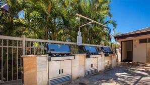 A row of barbecue grills with a sign above them, a wheelchair-accessible entrance, and a stone-tiled patio area. - Maui Banyan ground floor 2 full baths,steps to Kamaole 2,great walking location. (Kihei)