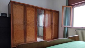 A room with a bed, a wooden wardrobe, and a window with curtains.