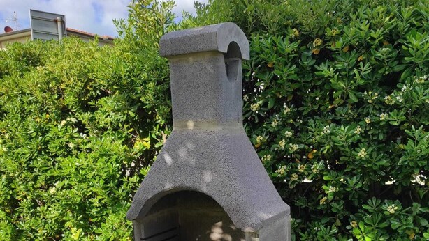 A stone-built outdoor oven in a garden setting.