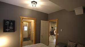 Une chambre à coucher avec un lit, une porte en bois, un schéma encadré accroché au mur et un canapé.