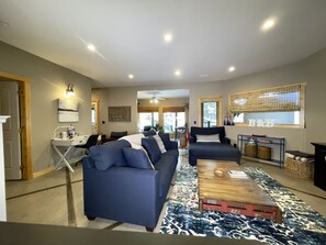 A spacious living room with a large blue sofa set, a wooden coffee table, and a patterned rug.
