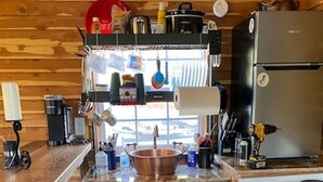 Een kleine keuken met een fornuis, koelkast en een klein aanrechtblad met een spoelbak.
