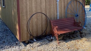 A wooden shed with a red roof, a bench, and a large blue wheel.