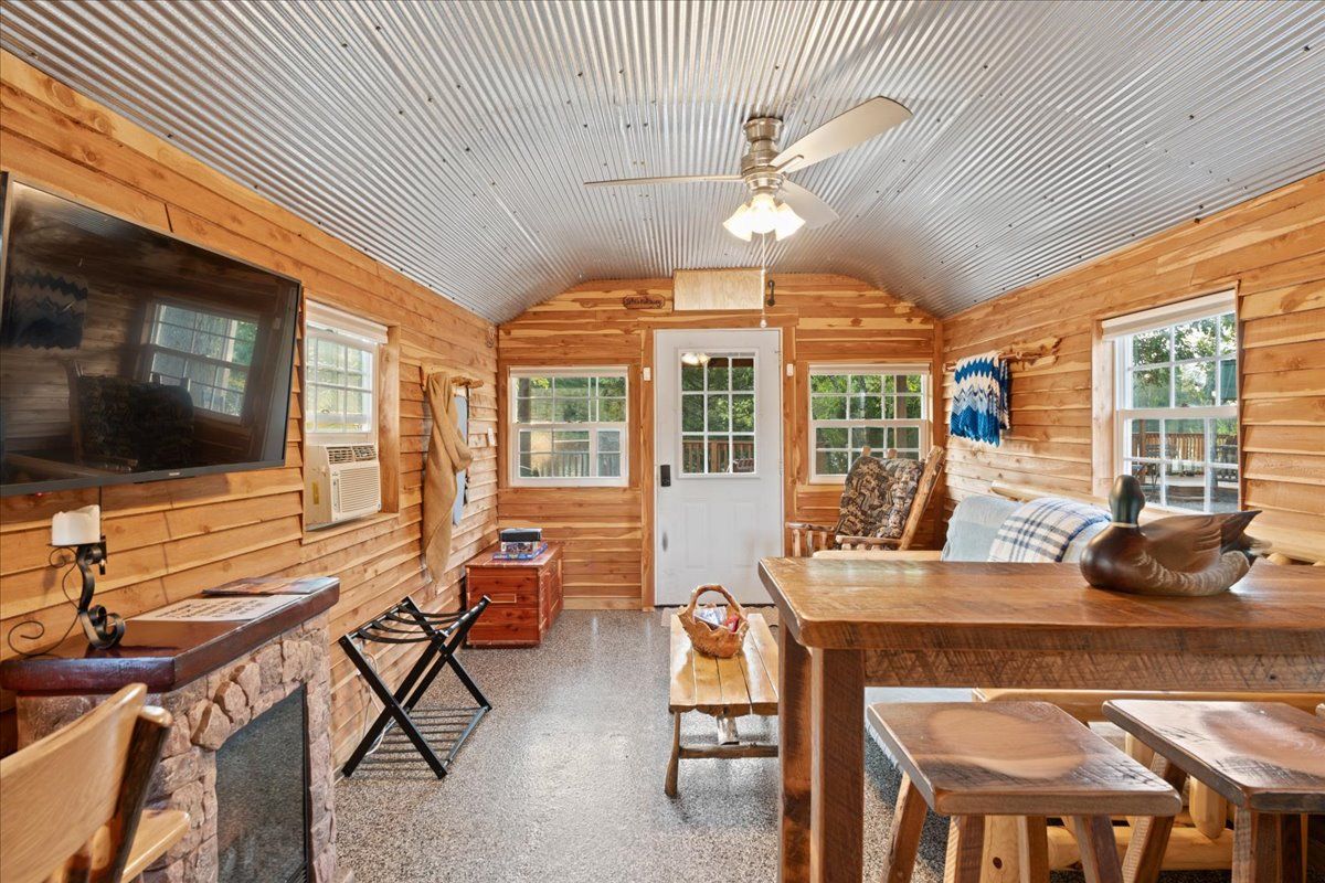 Interno di una baita in legno con camino, mobili in legno e televisore.