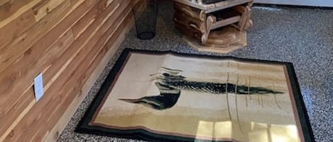 L’intérieur d’une cabane en bois, avec un fauteuil à bascule, une porte et une fenêtre.