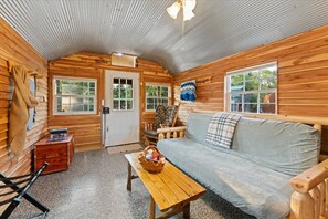 L’intérieur chaleureux d’un chalet, avec un décor en bois, un canapé, une table et une chaise.