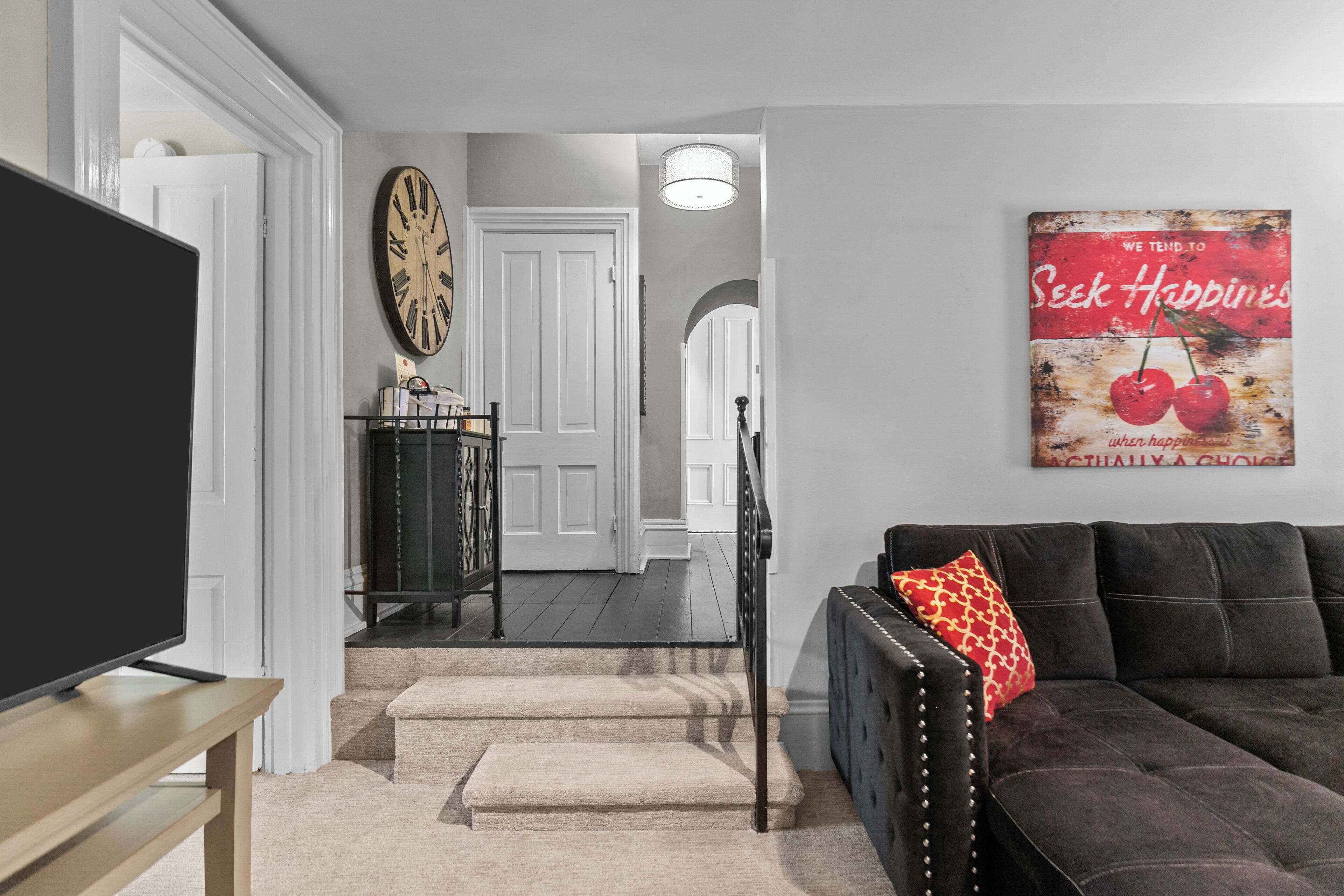 A living room with a TV, a sofa, a coffee table, and a staircase leading to another room.