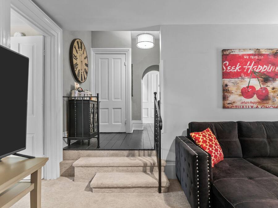 A living room with a TV, a sofa, a coffee table, and a staircase leading to another room.