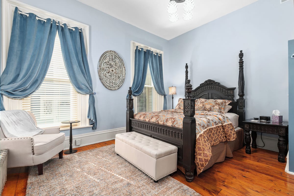 A bedroom with a large bed, a chair, a bench, and a nightstand.