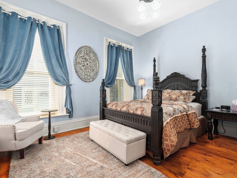 A bedroom with a large bed, a chair, a bench, and a nightstand.