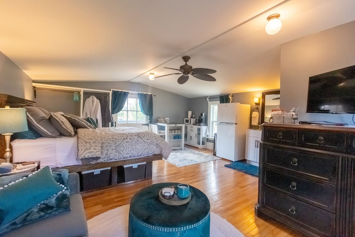 A bedroom with a bed, a dresser, a desk, and a television.