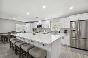 Una cocina moderna con una isla grande, electrodomésticos de acero inoxidable y una paleta de colores neutros.