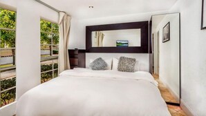 Ein Schlafzimmer mit einem großen Bett, einem Spiegel darüber und Blick auf Grün.