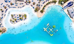 An aerial view of a beach resort with multiple swimming areas, sun loungers, and a water slide. - 28 RM Disney Villas Including Pool-golf-tennis (Davenport)