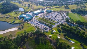 Vista aérea de un campo de golf con varios edificios, zonas de estacionamiento y cuerpos de agua.