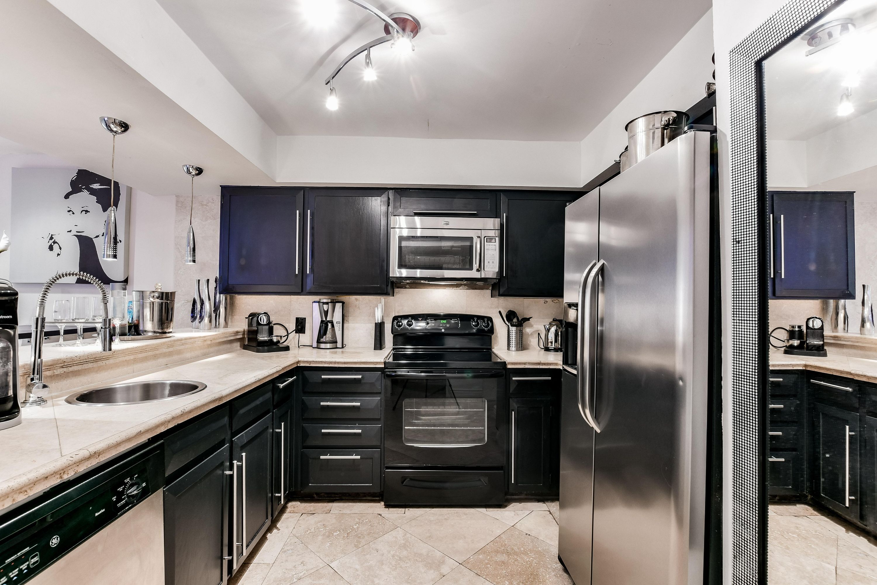 A modern kitchen with stainless steel appliances, black cabinets, and a dishwasher.