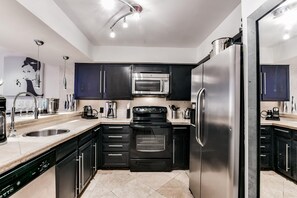 A modern kitchen with stainless steel appliances, black cabinets, and a dishwasher. - 12 Room Scottsdale Golf Tennis Lake Resort Villa (Paradise Valley)