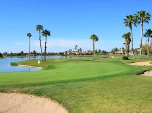 A golf course with a water hazard, palm trees, and a clear sky. - 12 Room Scottsdale Golf Tennis Lake Resort Villa (Paradise Valley)