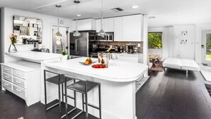 Une cuisine moderne dotée d’un îlot central, d’appareils électroménagers en acier inoxydable et d’un coin repas avec une banquette.